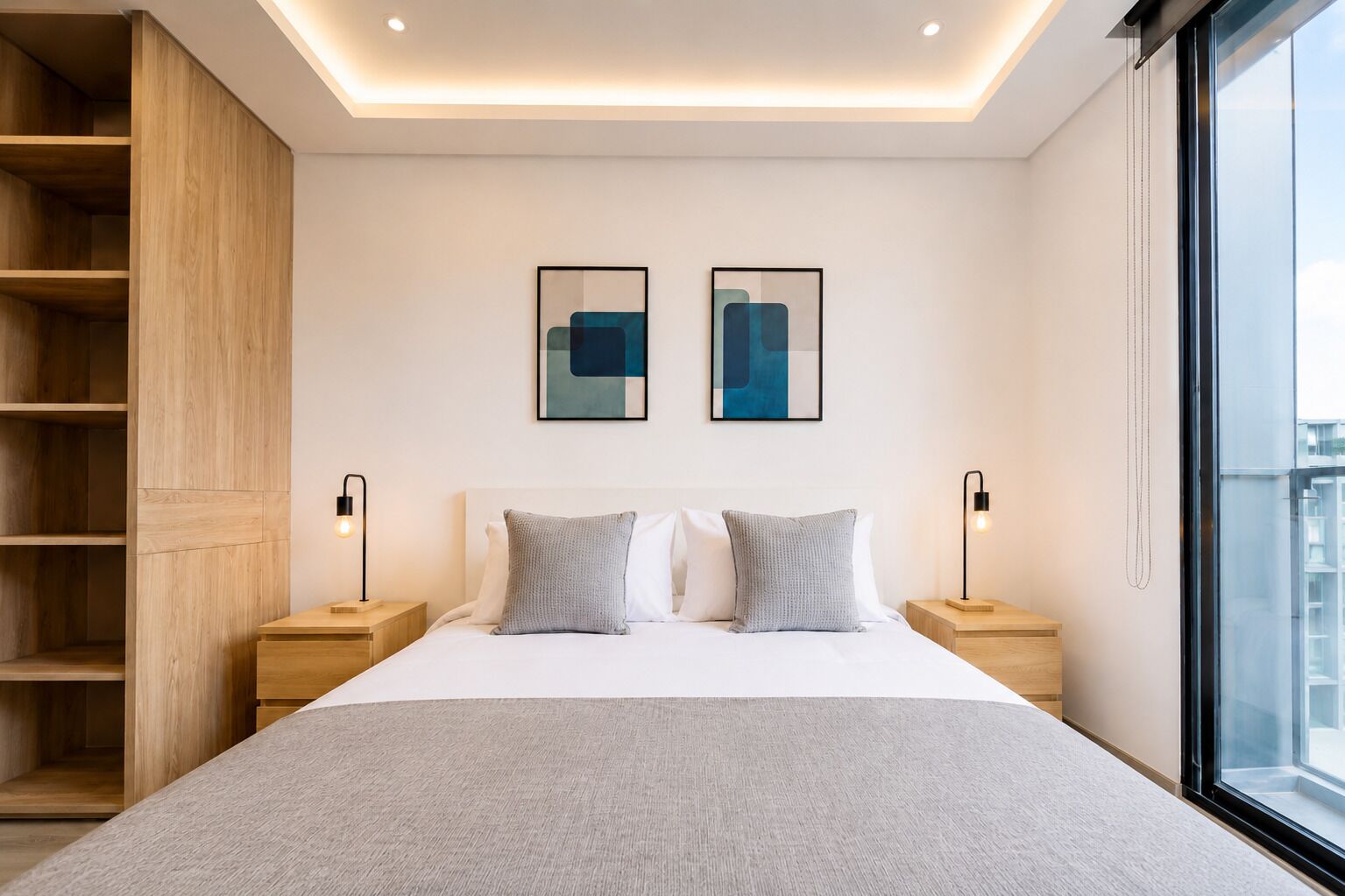 A modern bedroom with a large bed, two bedside tables, a built-in wooden shelving unit, and a large window.
