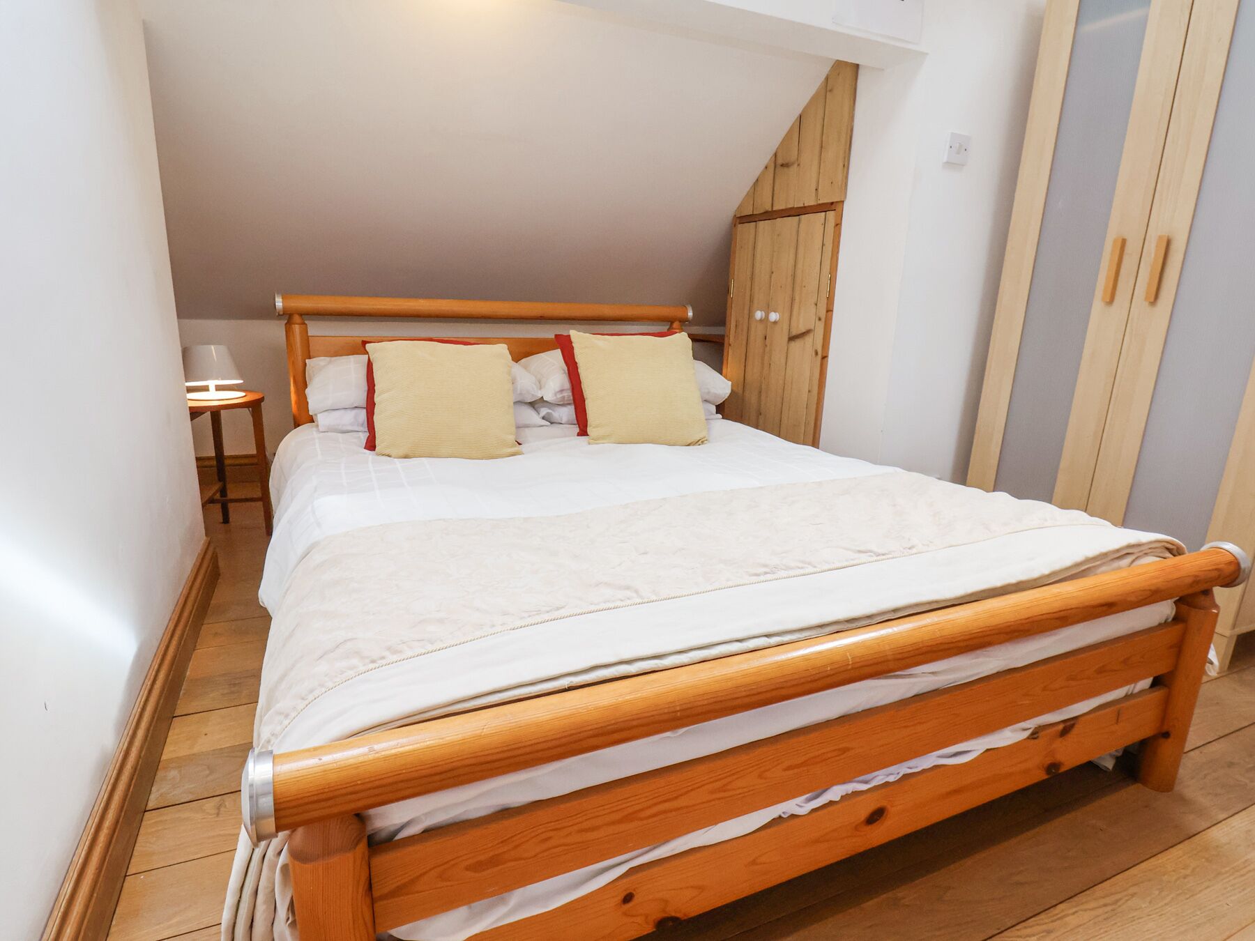 Un lit bien fait, avec un cadre en bois, une tête de lit et deux oreillers.