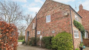 A traditional brick house with a gravel driveway, a small garden, and a clear sky. - The Barn - Poplar Farm (York)