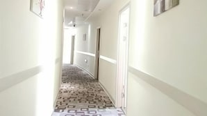 En hotellkorridor med ett mönstrat golv, vita väggar och dörrar som leder till rummen.