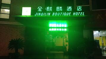 Ingången till Jingilin Boutique Hotel, med en tydlig skylt och en fasad som är upplyst i grönt.