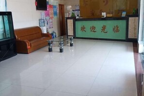 A reception area with a green counter, a brown sofa, and a glass-top table. - Jinqilin Hotel (Shanghai Xuanqiao) (Shanghai)
