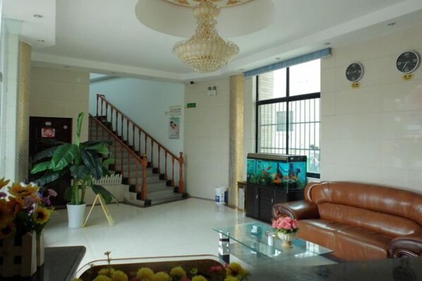 A spacious living area with a staircase, a glass coffee table, a leather sofa, and a large potted plant. - Jinqilin Hotel (Shanghai Xuanqiao) (Shanghai)
