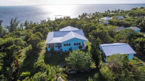 A coastal property with multiple buildings surrounded by lush greenery and a view of the ocean. - Sea Bird 3/3 Overlooking the Sea of Abaco with Private Beach & dock access (green turtle cay)