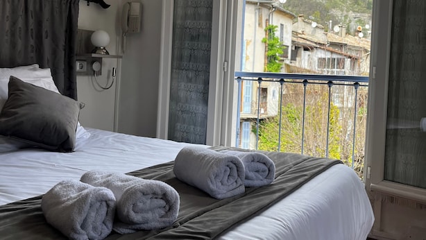 Et hotelværelse med en seng, en telefon og udsigt til et bjerg og bygninger.