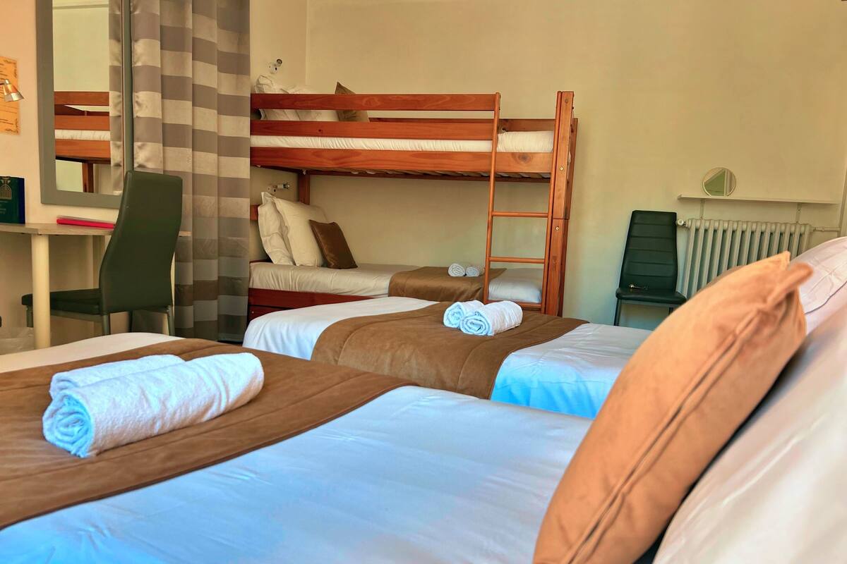 A hotel room with two beds, a desk, and a chair.