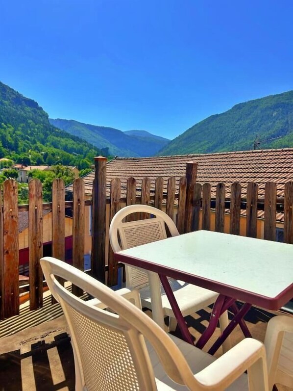 Een terras met een tafel en stoelen, met uitzicht op een bergachtig landschap.