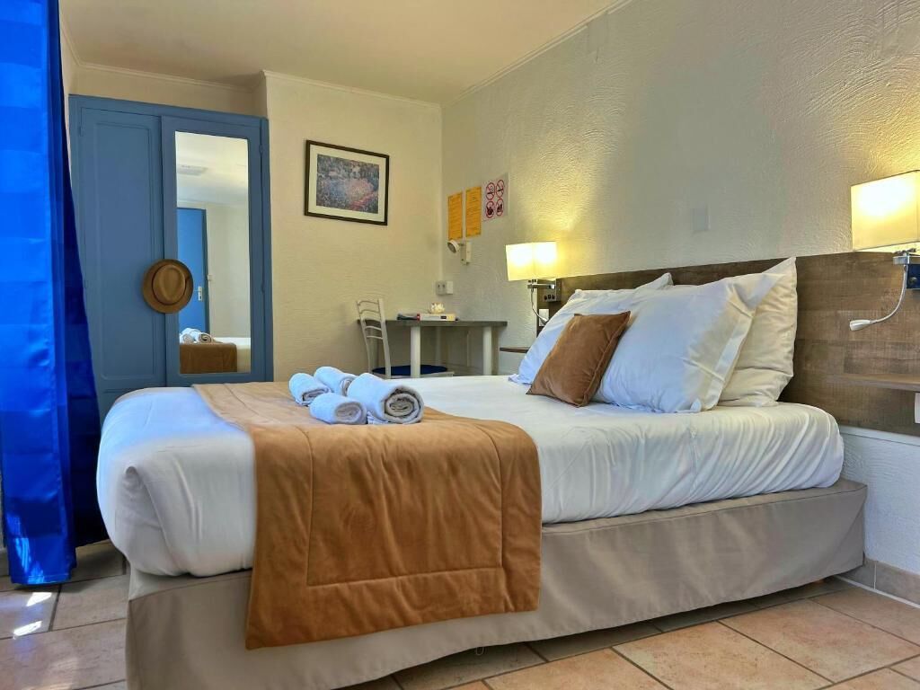 Een hotelkamer met een bed, een bureau, een stoel en een lamp.