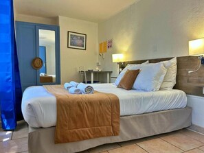 Een hotelkamer met een bed, een bureau, een stoel en een lamp.