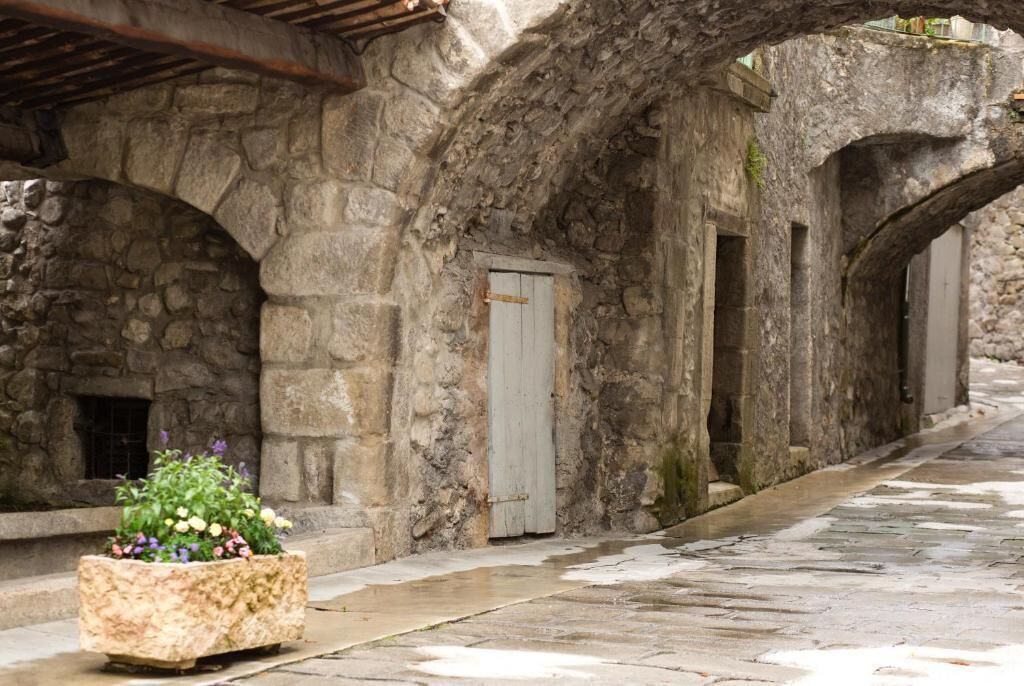 A stone corridor with arched ceilings and a planter with flowers.