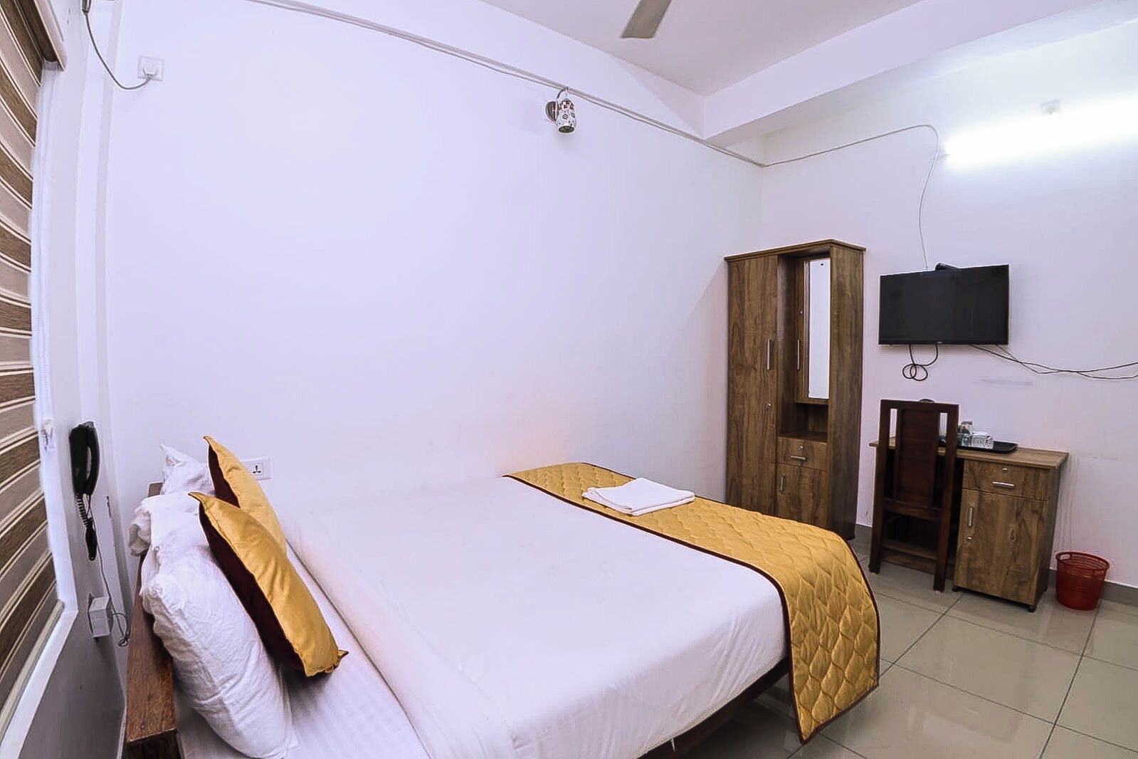 A bedroom with a bed, a wardrobe, a TV, and a telephone.