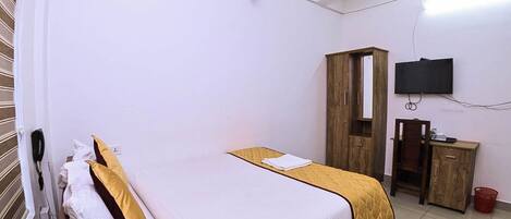 A bedroom with a bed, a wardrobe, a TV, and a telephone.