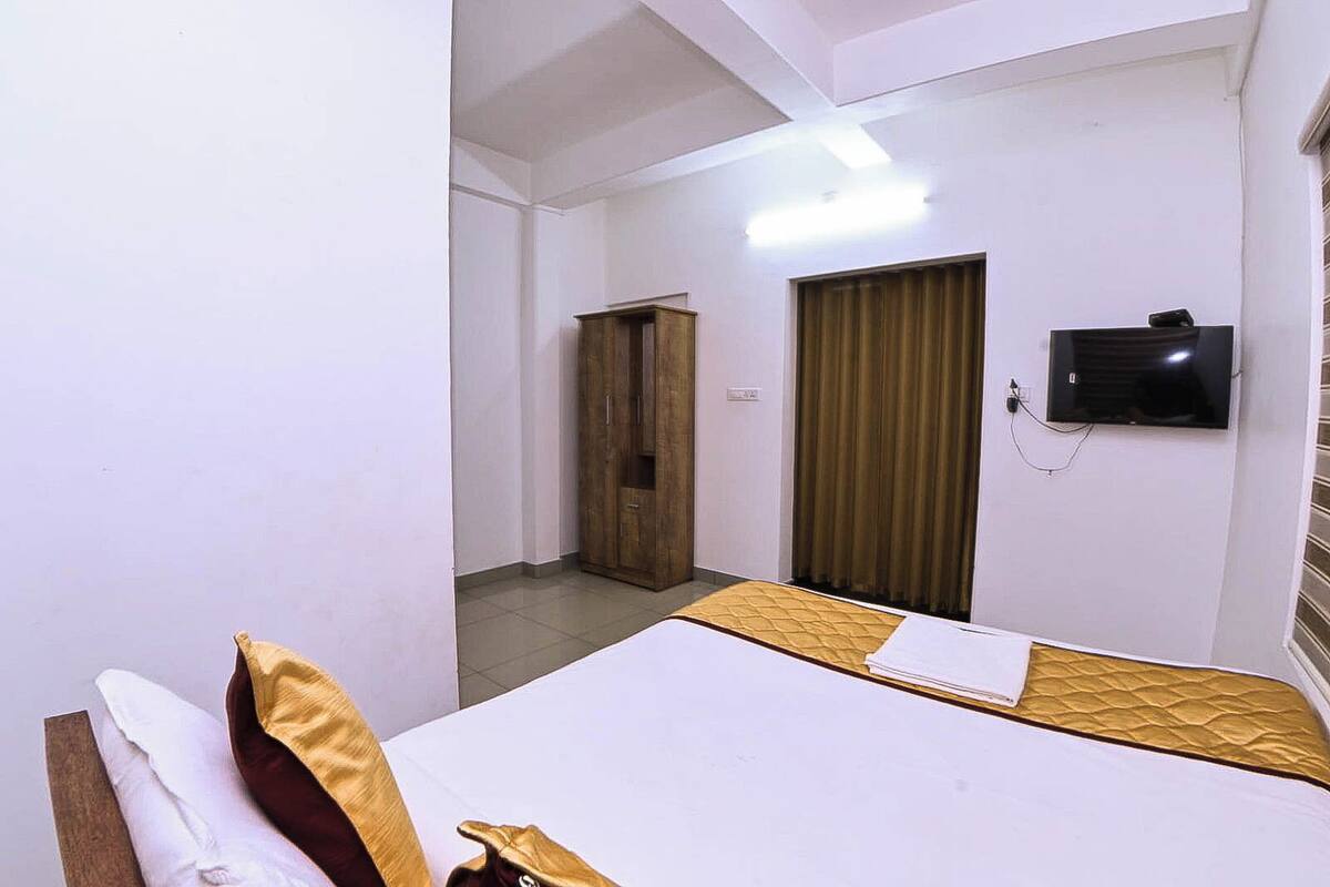A hotel room with a bed, a wardrobe, a television, and a curtain.