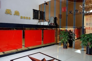 A hotel reception area with a red counter, a blackboard with information, and potted plants. - Aishang Hotel (Shanghai Guoquan Road) (Shanghai)