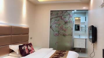 Ein Hotelzimmer mit Bett, einer Wanddekoration mit floralem Muster, einem Badezimmer mit Spiegel und einem an der Wand befestigten Fernseher.