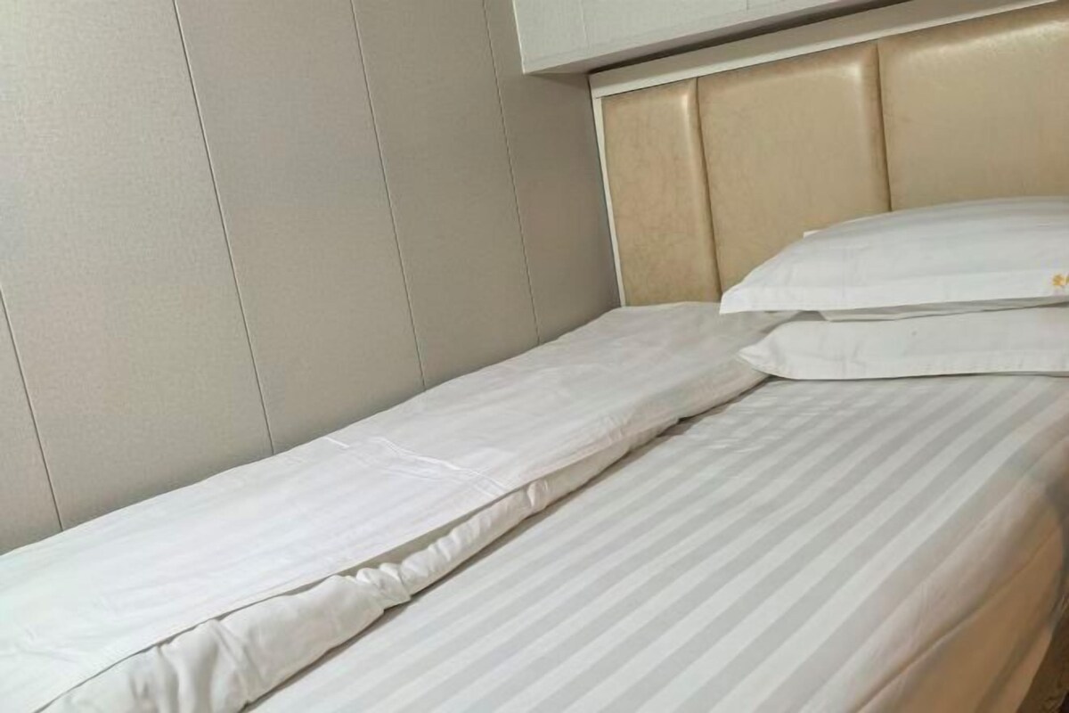 A single bed with a headboard, a pillow, and a white wall.
