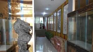 A hallway with a stone sculpture, a staircase, and framed calligraphy on the walls. - Aishang Hotel (Shanghai Guoquan Road) (Shanghai)