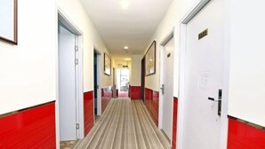A hotel corridor with red and white walls, striped carpet, and doors on both sides. - Aishang Hotel (Shanghai Guoquan Road) (Shanghai)