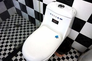A white toilet with a blue sticker in a bathroom with black and white checkered floor tiles. - Aishang Hotel (Shanghai Guoquan Road) (Shanghai)