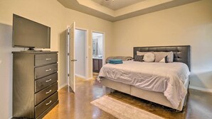 Ein Schlafzimmer mit Bett, Kommode, Fernseher und Deckenventilator.