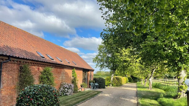 A brick building with a gravel driveway leading to a grassy area. - Pear Tree (Dereham)