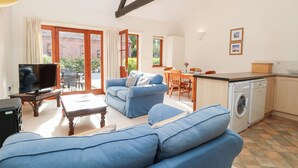 Ein Wohnzimmer mit einem blauen Sofa, einem Fernseher und einem Essbereich mit Tisch und Stühlen.
