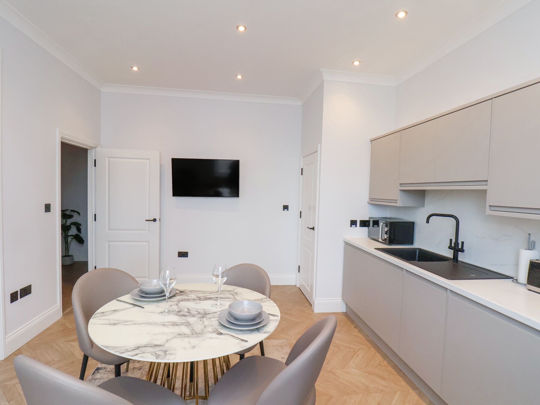 A modern kitchen with white cabinets, a black microwave, and a sink.