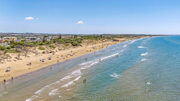A beach with clear water, sandy shore, and a few umbrellas. - Villa Marena by Villa Plus (Santa Maria del Focallo)