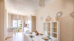 A dining area with a table set for four, a white cabinet, and decorative wall art. - Villa Marena by Villa Plus (Santa Maria del Focallo)