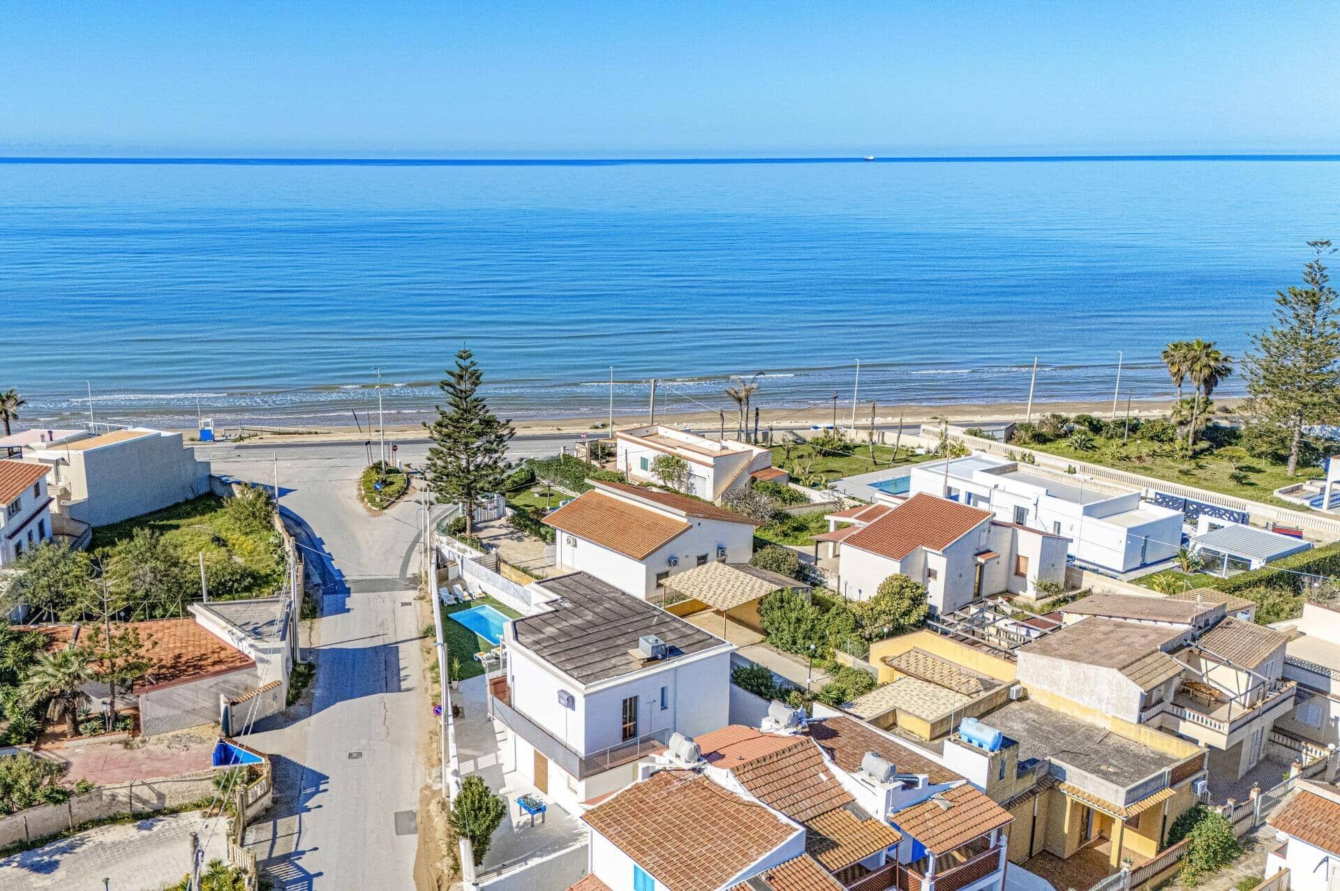 Ein Küstenwohngebiet mit Häusern, einer Straße und einem Strand im Hintergrund.
