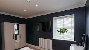 A modern bathroom with a large mirror, a white sink, and a window with blinds. - The Salisbury 1 Bed Classic Apartment (Scarborough)