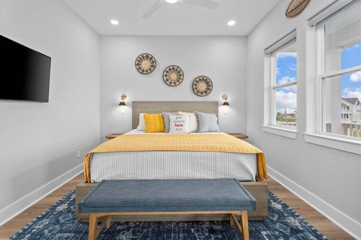 Un dormitorio con cama, lámparas de noche, un televisor de pantalla plana, decoración mural y una ventana con vistas.