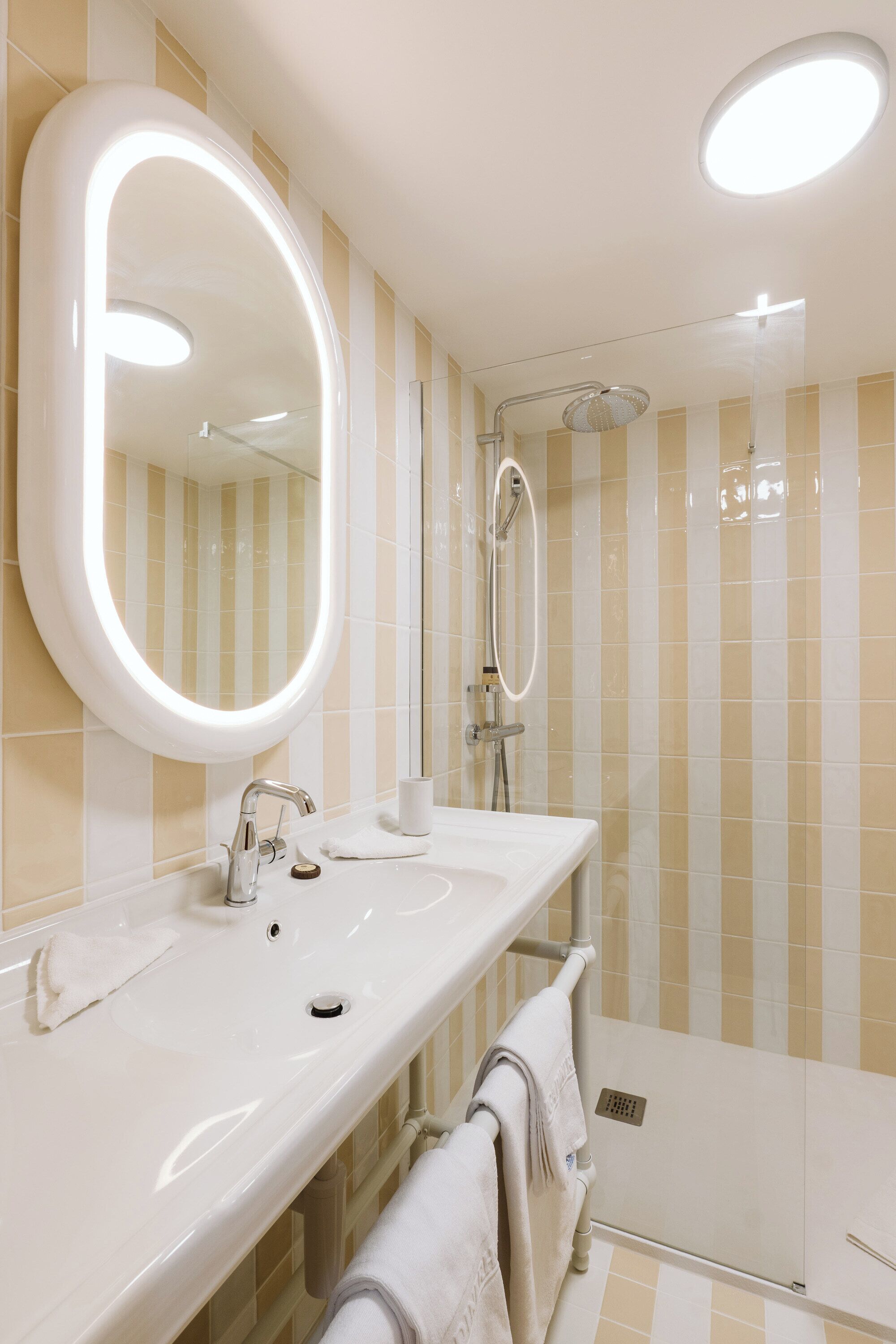Un baño moderno con un espejo grande, un lavamanos y una ducha.