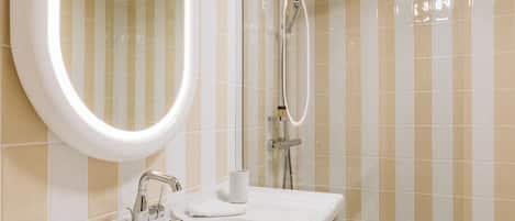 Un baño moderno con un espejo grande, un lavamanos y una ducha.