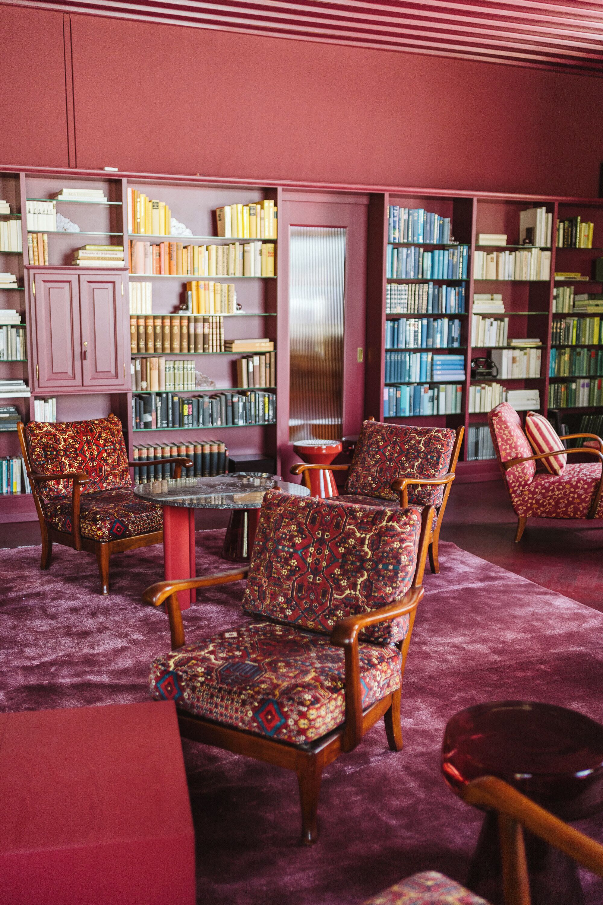 Una biblioteca con varias sillas de madera y una mesa redonda, rodeada de estanterías llenas de libros.