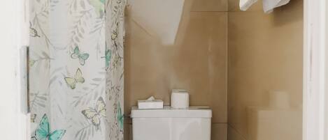 A small bathroom with a toilet, a shower curtain with a butterfly pattern, and a towel rack.