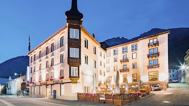 Un hôtel doté d’une tour d’angle remarquable, de nombreux balcons et d’un hall d’entrée bien éclairé, agrémenté d’un espace extérieur avec des sièges.