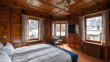 Une chambre dans un chalet en bois, avec un grand lit, une télévision et une vue sur un paysage enneigé.