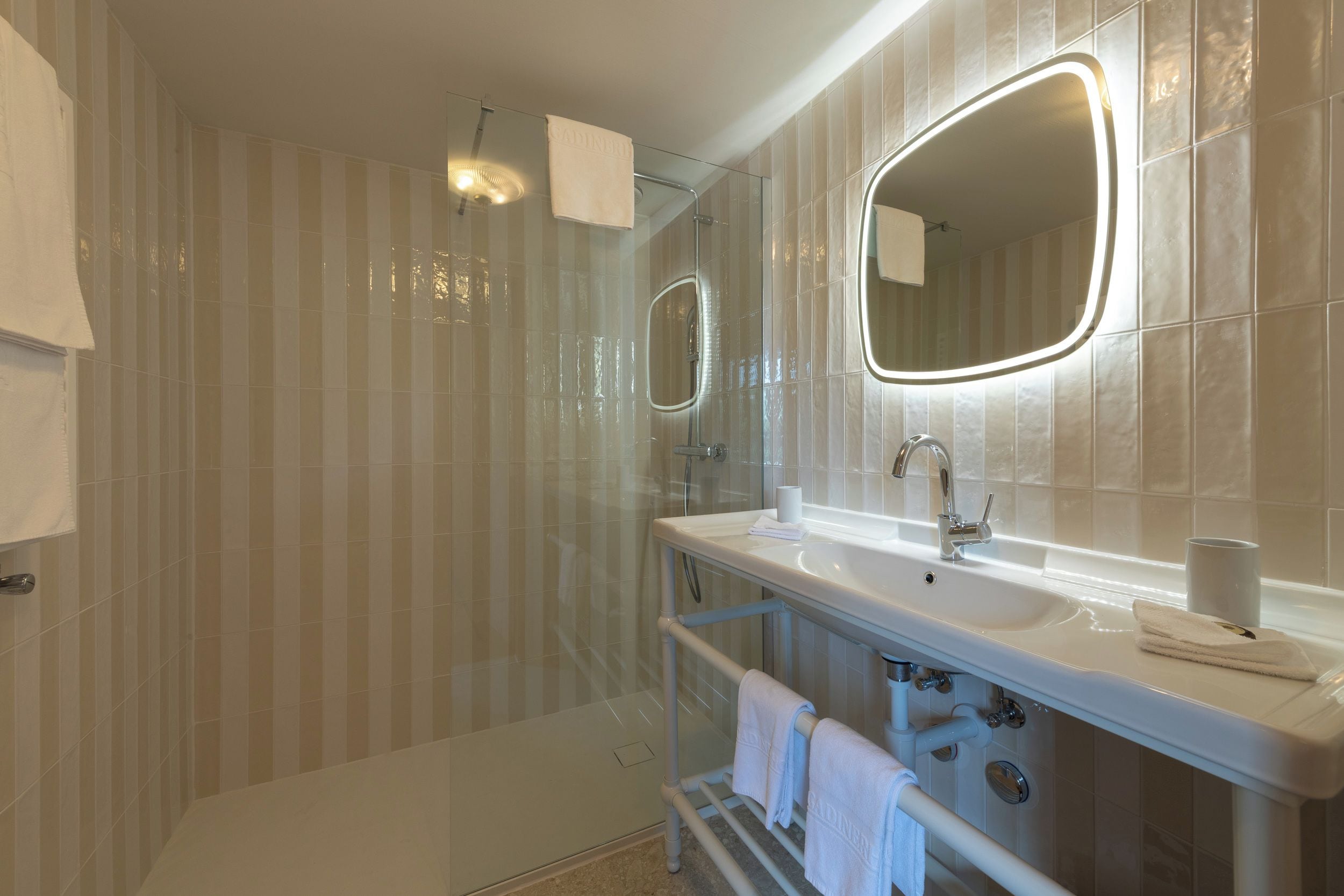 A modern bathroom with a large mirror, a shower, and a vanity with a sink.