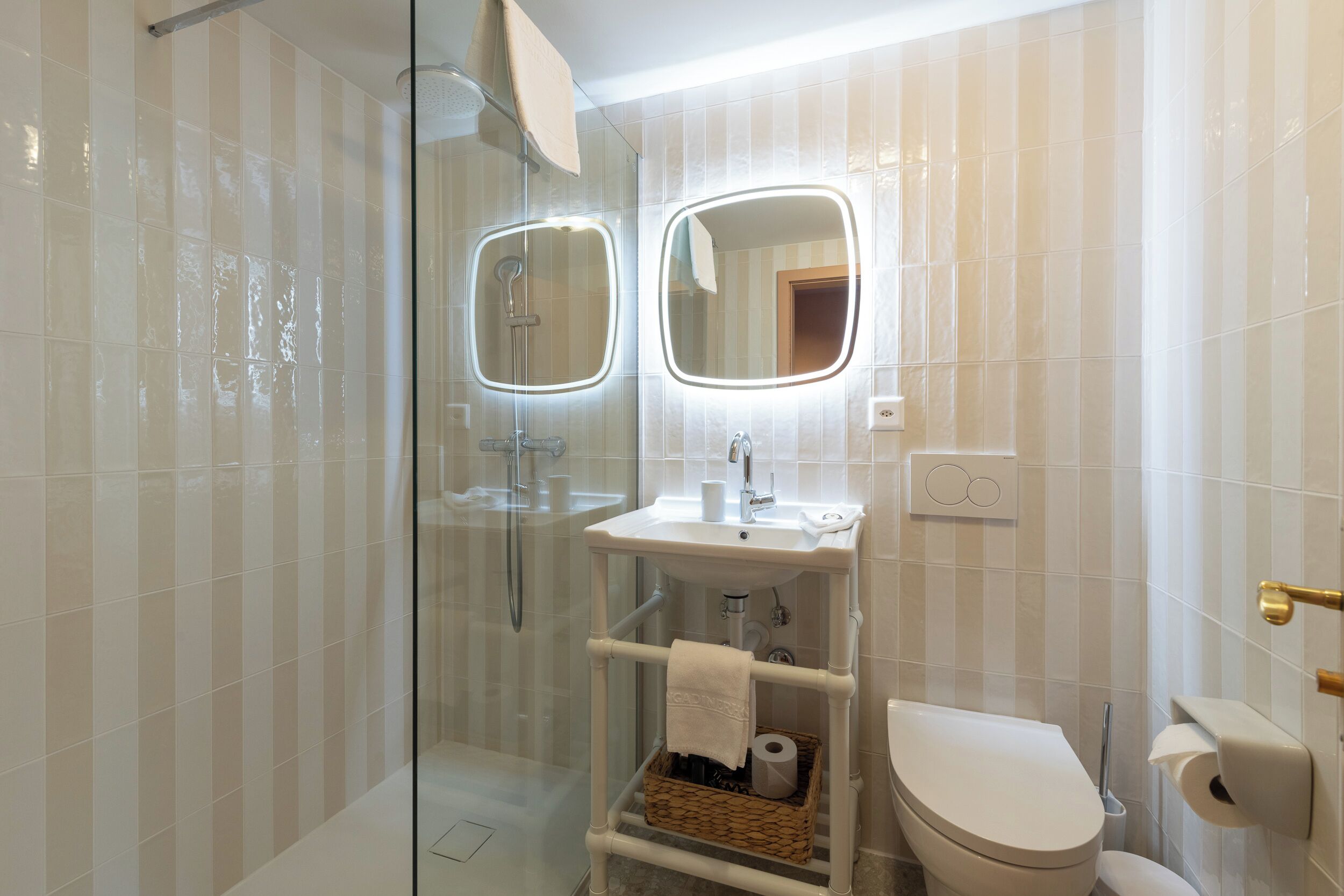 A modern bathroom with a glass-enclosed shower, a white sink with a mirror, and a toilet.