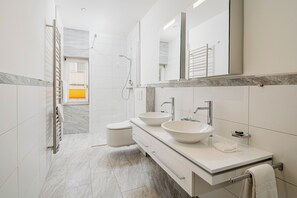 A modern bathroom with two sinks, a walk-in shower, and a large mirror. - Boutique Hotel Engadinerhof – A Home for Generation (Pontresina)