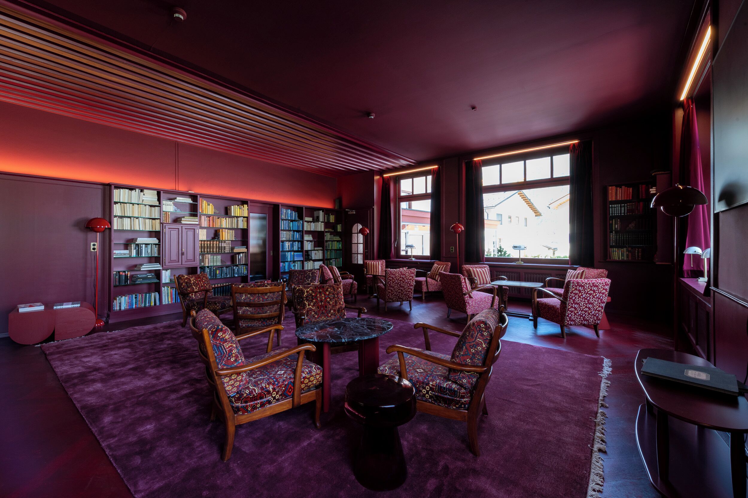 Una biblioteca con estanterías, asientos cómodos y ventanas amplias.