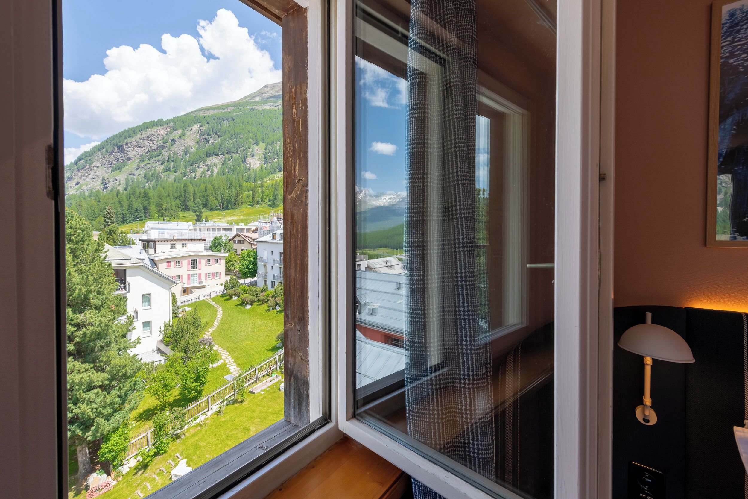 Una habitación con un amplio ventanal que ofrece vistas a un paisaje verde y edificios.