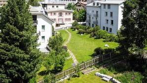 A residential area with houses, a grassy lawn, and a mountainous backdrop.
