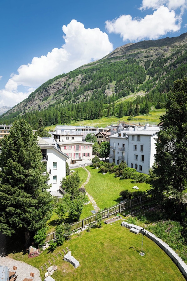 A residential area with houses, a grassy lawn, and a mountainous backdrop.