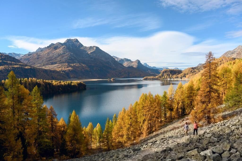 A mountainous landscape with a lake and autumn-colored trees.