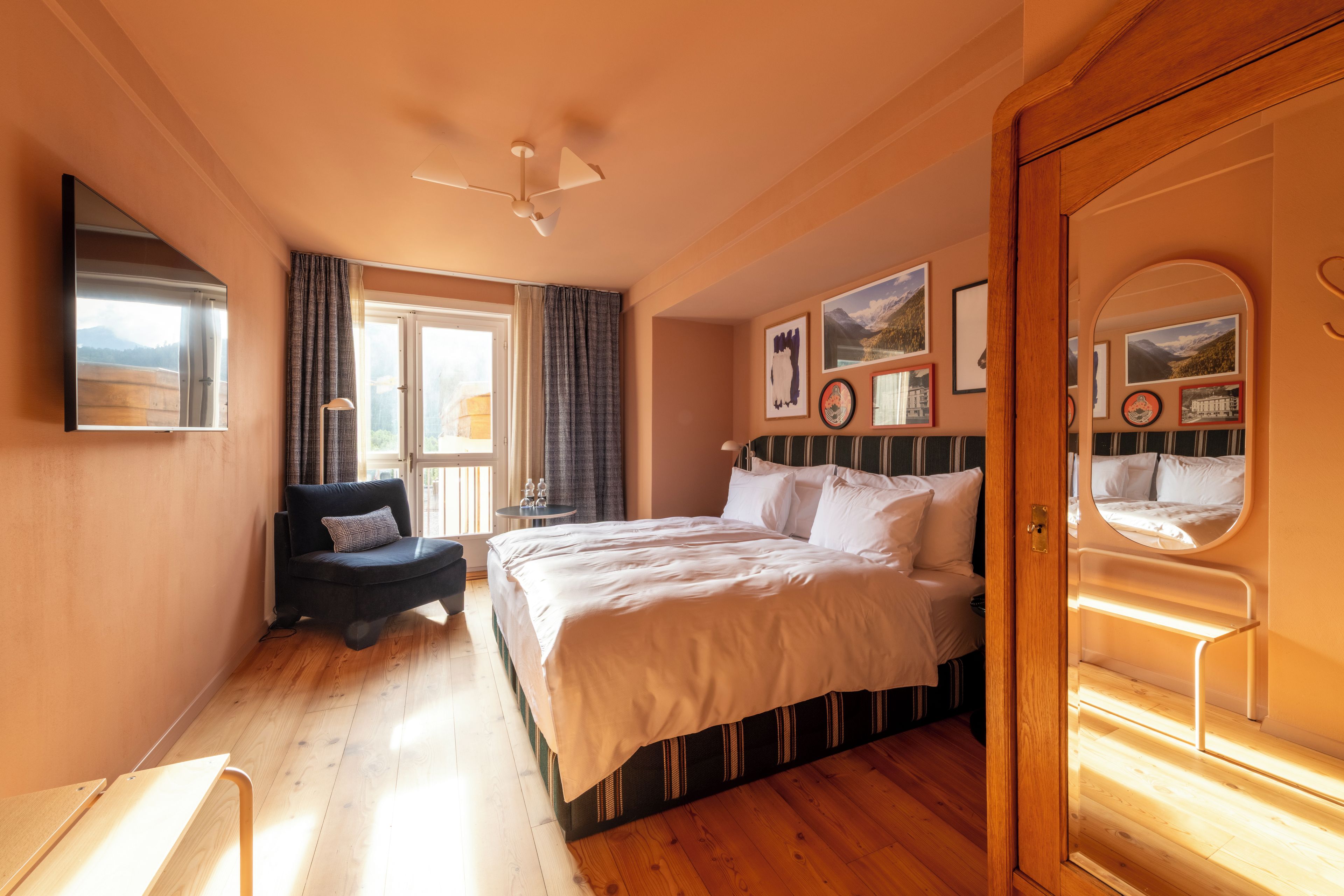 A bedroom with a bed, a chair, a ceiling fan, and a window with curtains.