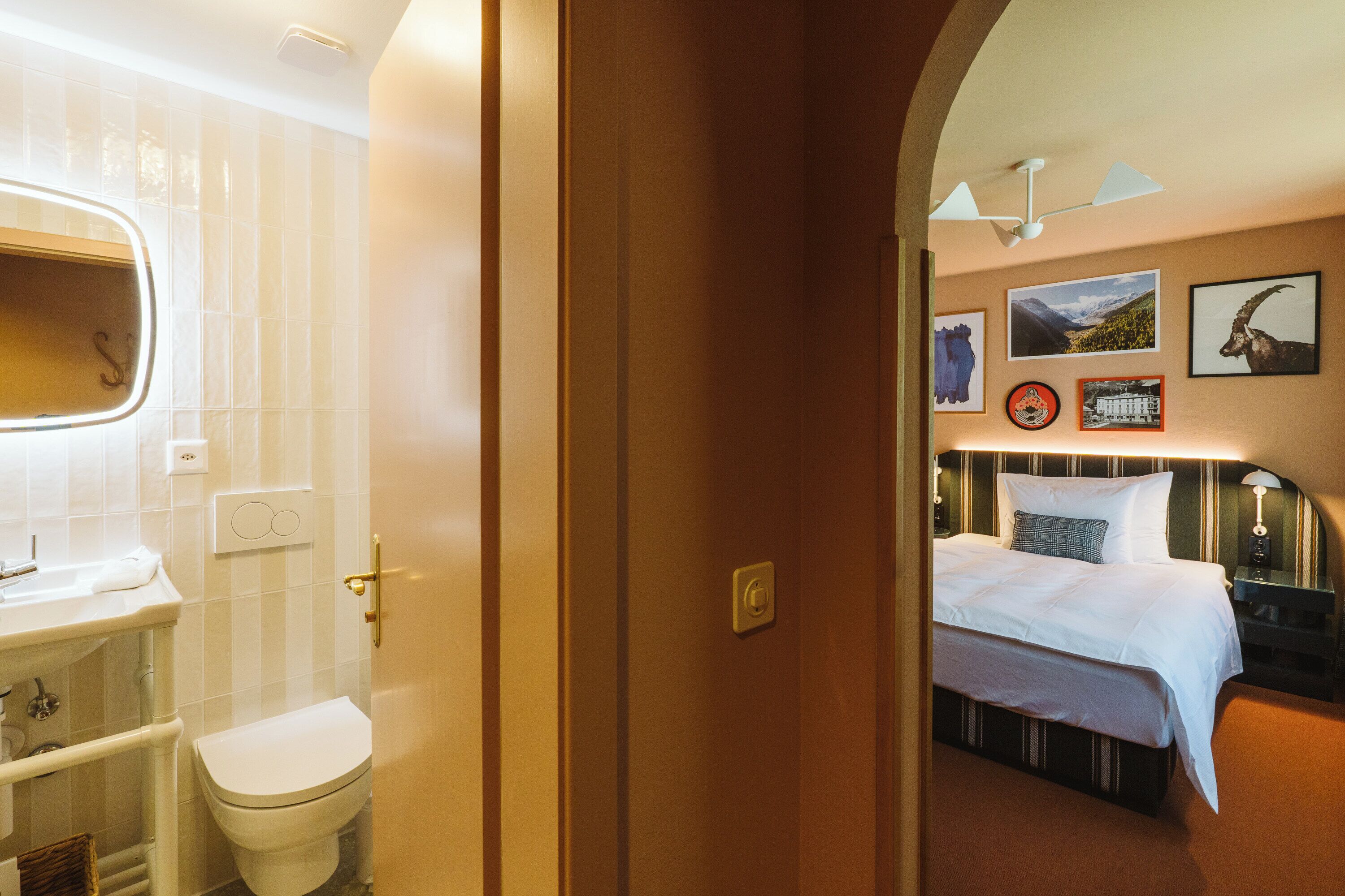 Una habitación de hotel con baño, una cama y una pared con cuadros.