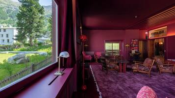 A room with a view of a mountain, a red lamp, a purple carpet, and a bookshelf.