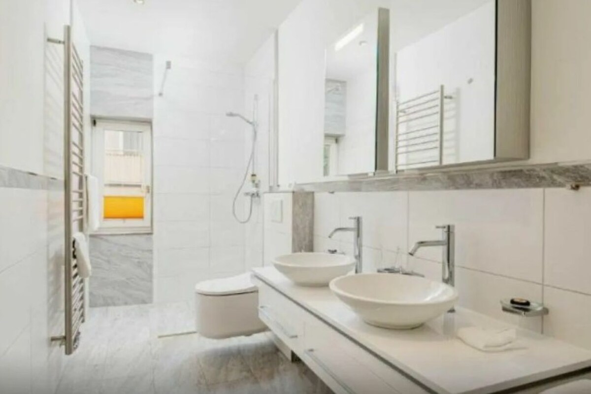 A modern bathroom with two sinks, a shower, and a toilet.